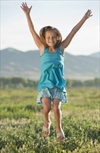 Young girl jumping in field. Photo. Mike Kemp
