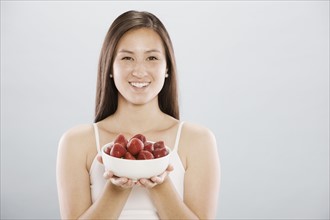 Brunette woman holding a bowl of strawberries. Photo. FBP