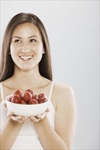 Brunette woman holding a bowl of strawberries. Photo. FBP