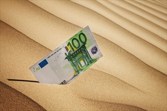 100 euro bill in sand. Photo : Mike Kemp