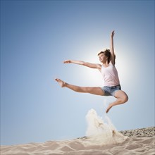 Female dancer jumping in sand. Photo : Mike Kemp