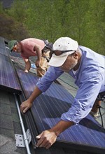Construction workers installing solar panels on roof. Photo : Shawn O'Connor