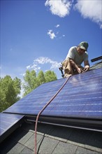 Construction worker installing solar panel on roof. Photo : Shawn O'Connor