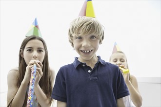 Three children wearing birthday hats. Photo : momentimages