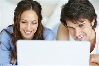 Couple looking at laptop together. Photo : momentimages