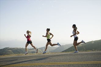 Runners training on side of a road.