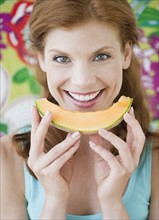 Woman eating a slice on cantaloupe. Photo : Jamie Grill