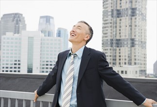 Happy businessman standing outdoors with eyes closed. Photo : Jamie Grill