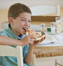 Boy (10-11) eating pizza. Photo : Daniel Grill