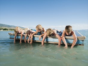 Kids (2-3,6-7,8-9,10-11,12-13) playing on raft on lake.