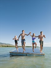 Kids (6-7,8-9,10-11,12-13) playing on raft on lake.