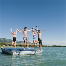 Kids (6-7,8-9,10-11,12-13) playing on raft on lake.