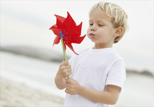 Portrait of boy (4-5) playing with pinwheel on beach. Photo : Momentimages