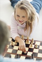 Granddaughter (10-11) playing chess with grandfather. Photo : Momentimages