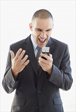 Angry businessman shouting at mobile phone. Photo : Momentimages