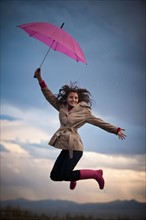 Young woman with umbrella under overcast sky. Photo : Mike Kemp