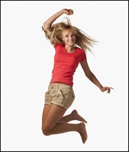 Young woman jumping on white background. Photo : Mike Kemp