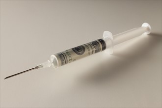 Studio shot of syringe with dollar banknote. Photo : Mike Kemp