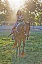 Girl (8-9) riding horse in paddock. Photo : Mike Kemp