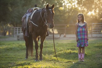 Girl (8-9) standing with horse in paddock. Photo : Mike Kemp