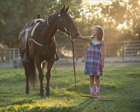 Girl (8-9) stroking horse in paddock. Photo : Mike Kemp