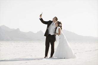 Bride and groom photographing themselves in desert. Photo : FBP
