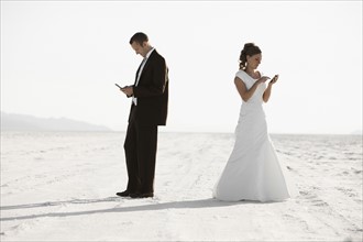 Bride and groom texting in desert. Photo : FBP