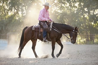 Senior man horseback riding in ranch. Photo : Mike Kemp