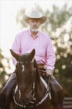 Portrait of senior man horseback riding in ranch. Photo : Mike Kemp