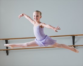 Portrait of ballet dancer (6-7) leaping in dance studio. Photo : Mike Kemp