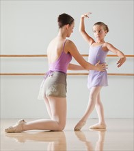 Female instructor training ballet dancer (6-7) in dance studio. Photo : Mike Kemp