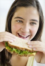 Girl (12-13) eating sandwich.