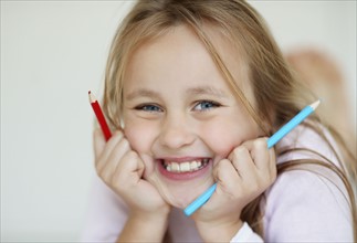 Girl (10-11) holding red and blue pencils. Photo : Momentimages
