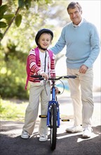 Portrait of grandfather and granddaughter (10-11) with bike. Photo : Momentimages