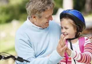 Happy grandfather and granddaughter (10-11) with bike. Photo : Momentimages