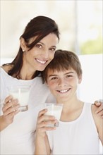 Portrait of smiling mother and son (12-13)  with glasses of milk. Photo : Momentimages