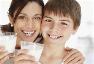 Portrait of smiling mother and son (12-13)  with glasses of milk. Photo : Momentimages