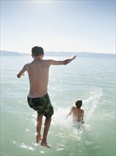 Boys (10-11,12-13) jumping into lake.