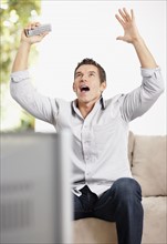 Man cheering in front of television. Photo : Momentimages