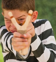Boy (10-11) using slingshot. Photo : Daniel Grill