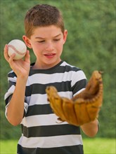 Boy (10-11) holding baseball and baseball glove. Photo : Daniel Grill