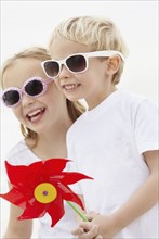 Girl (10-11) and boy (4-5) wearing sunglasses on beach. Photo : Momentimages