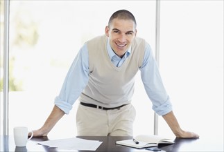 Cheerful office worker with hands behind back. Photo : Momentimages