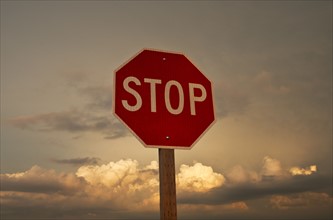 USA, South Dakota, Badlands National Park, Stop sign against sky at sunset.