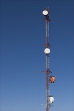 Tele-communications relay tower against blue sky.