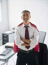 Portrait of smiling businessman wearing red cape. Photo : Jamie Grill