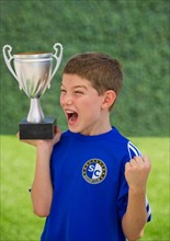 Boy (10-11) holding trophy and cheering. Photo : Daniel Grill