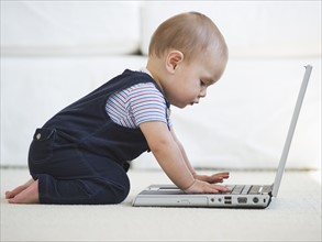 Baby boy (12-17 months) using laptop. Photo : Daniel Grill