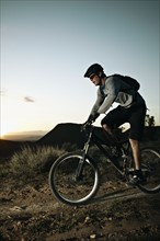 Man mountain biking at sunset. Photo : Shawn O'Connor