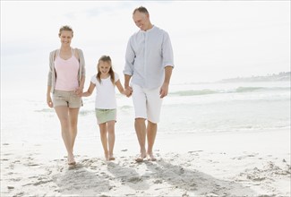 Girl (10-11) playing on beach with parents. Photo : Momentimages